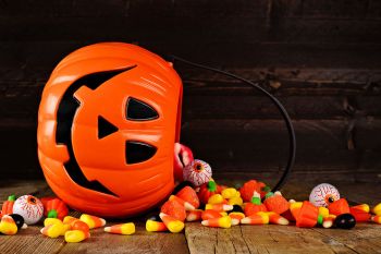 An overturned jack-o-lantern with candy spilling out of it